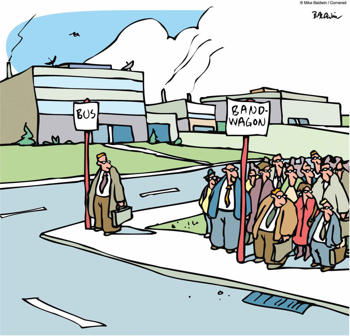 The cartoon shows a neighbourhood, where one man is seen standing next to a signboard which reads, ‘BUS’ and a crowd of women and men is seen standing next to the signboard which reads, ‘Bandwagon.’ All people are looking towards their left.