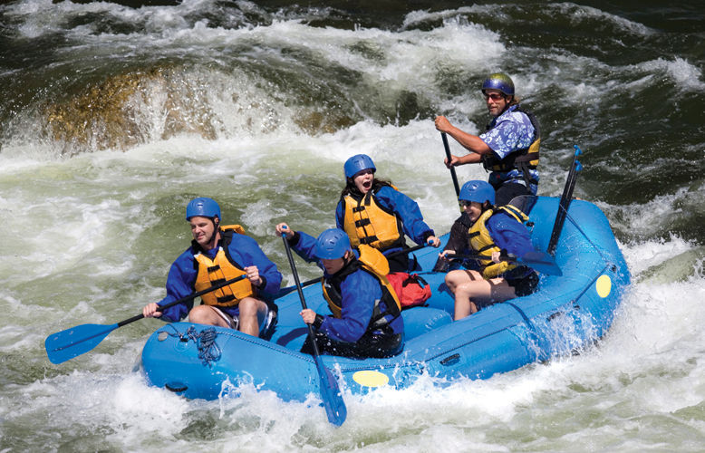 The photograph shows five people are seen doing rafting in a water body. All of them look thrilled and excited.