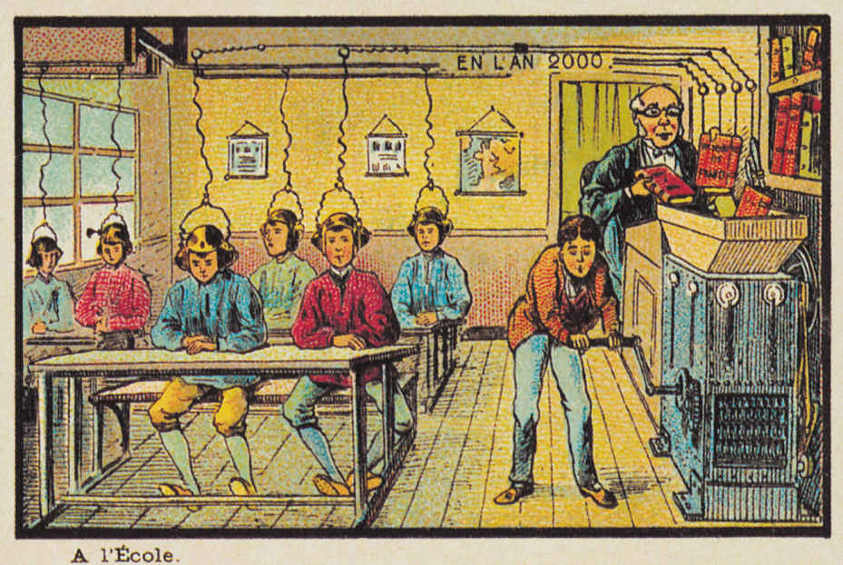 The image shows a class room where students are sitting in rows on benches wearing head phones which are hanging from the roof, wired and connected to books which are kept on a funnel of the machine. The teacher, who is sitting next to the machine, is handling the books. The machine is run by a boy who is rotating the handle of it. The teacher and machine are seen in the left hand side from the class. We can also see maps and charts hanging on one of the wall of the classroom. There is a bookshelf next to the machine where the teacher is sitting.